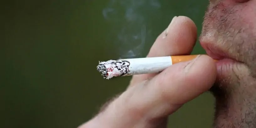 Un homme fume une cigarette