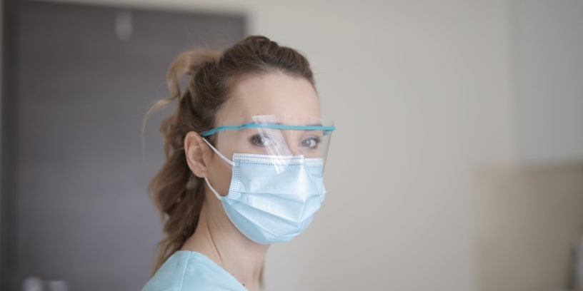 Une infirmière portant un masque chirurgical et des lunettes de protection